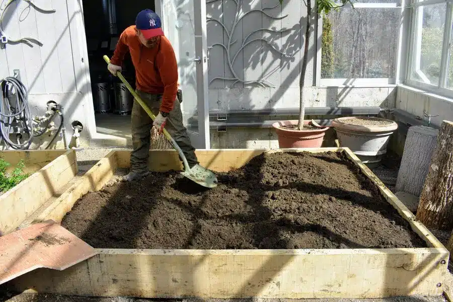 shovel and rake leveling raised garden bed